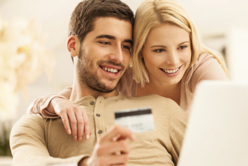 couple looking at computer holding credit card