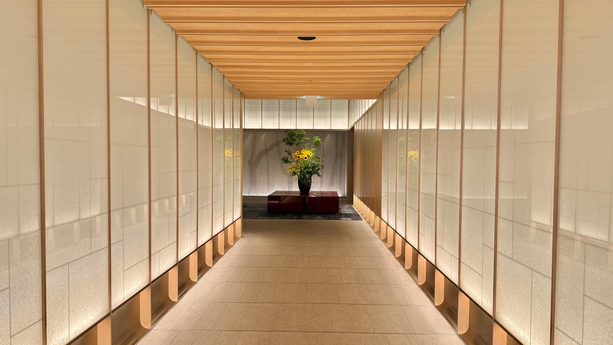 Lit arrival corridor lined with translucent screen panels leading into the lobby at The Ritz-Carlton, Fukuoka