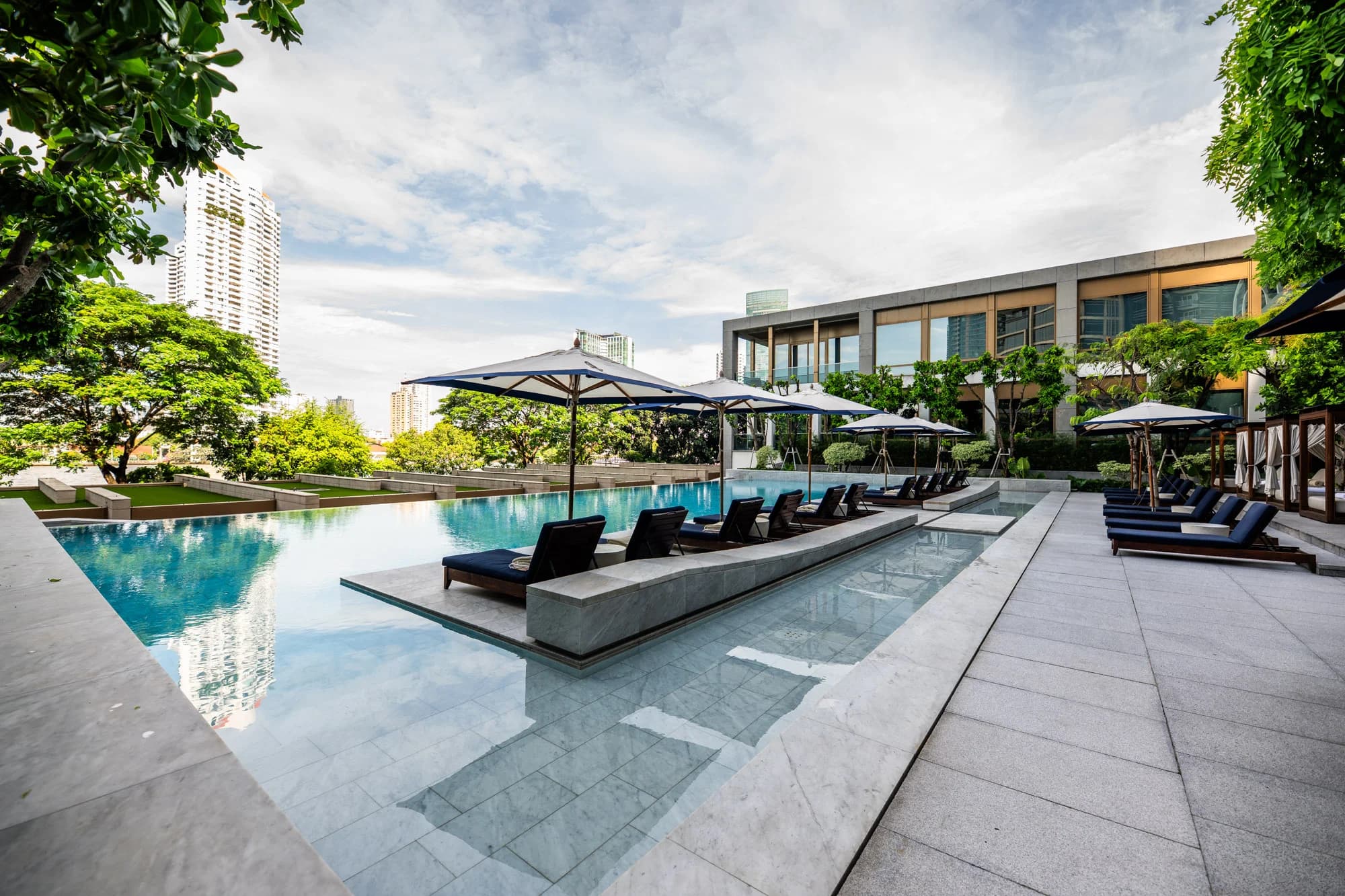 Infinity pool with umbrellas and loungers at Capella Bangkok